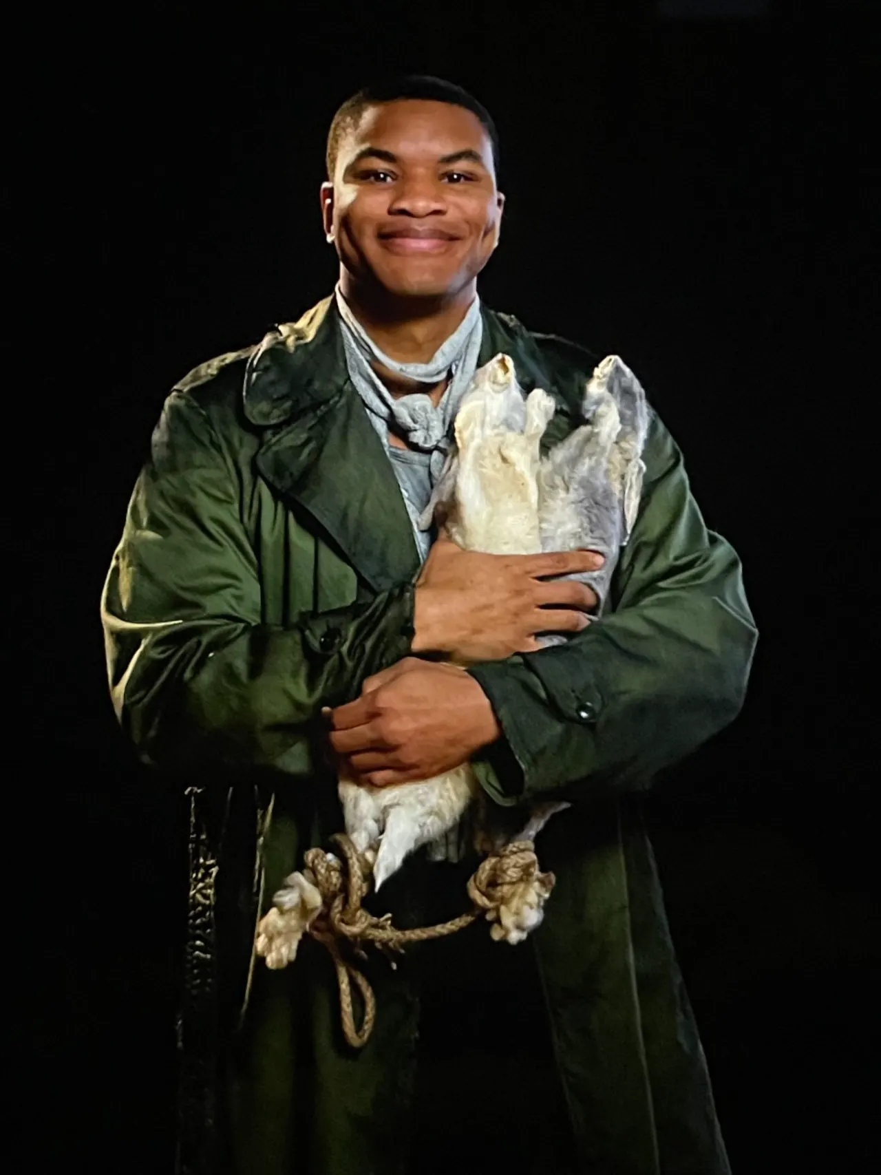 Costumed performer lit against black — The Hunger Games Live