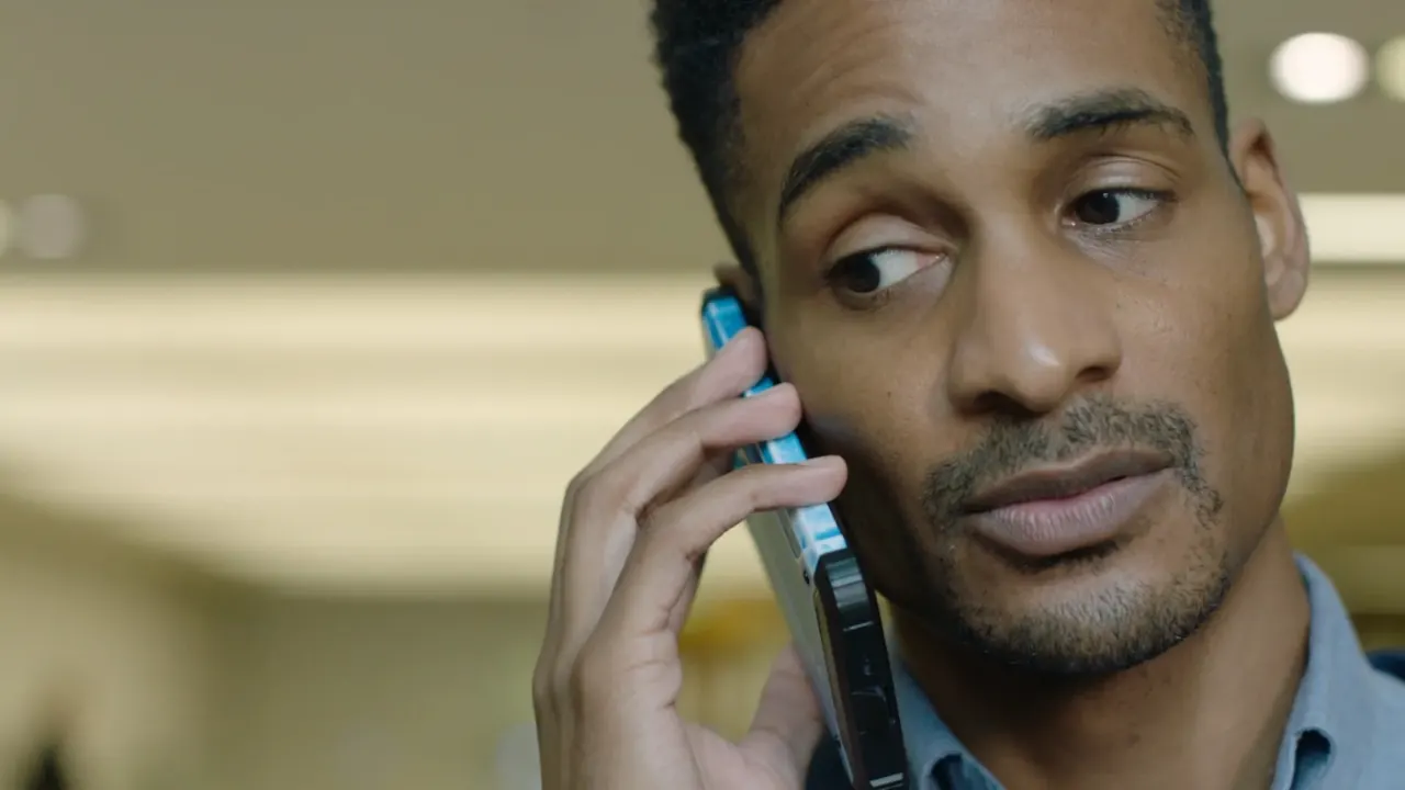 Bright naturalistic interior — man on a phone, frame from the Nomura commercial